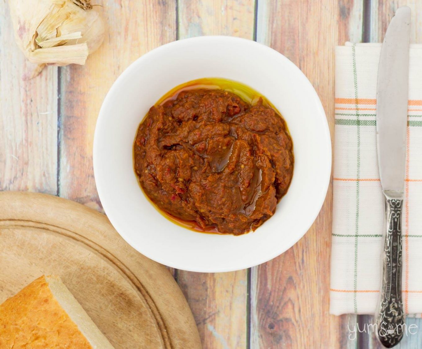 overhead view of a bowl of ajvar with a knife and some bread | yumsome.com