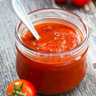 A small jar of Italian tomato sauce on a grey table.