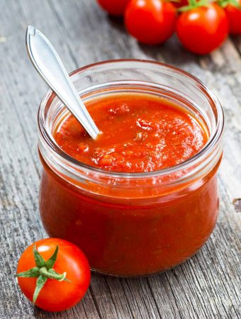 A small jar of Italian tomato sauce on a grey table.