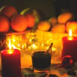 Candlelit glasses of mulled wine, with seasonal fruits in the background.