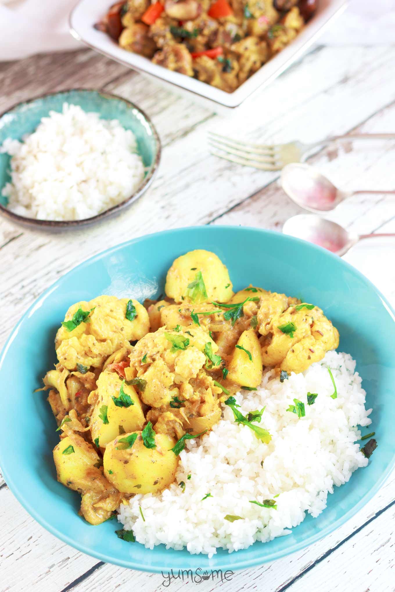 A bright blue bowl containing rice and simple vegan aloo gobi masala.