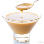 A spoonful of vegan condensed milk drizzling into a glass dish.