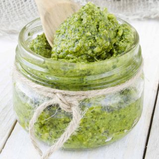 A jar of 5-minute vegan cashew pesto, with a wooden spoon in it.