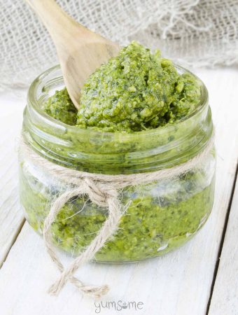 A jar of 5-minute vegan cashew pesto, with a wooden spoon in it.