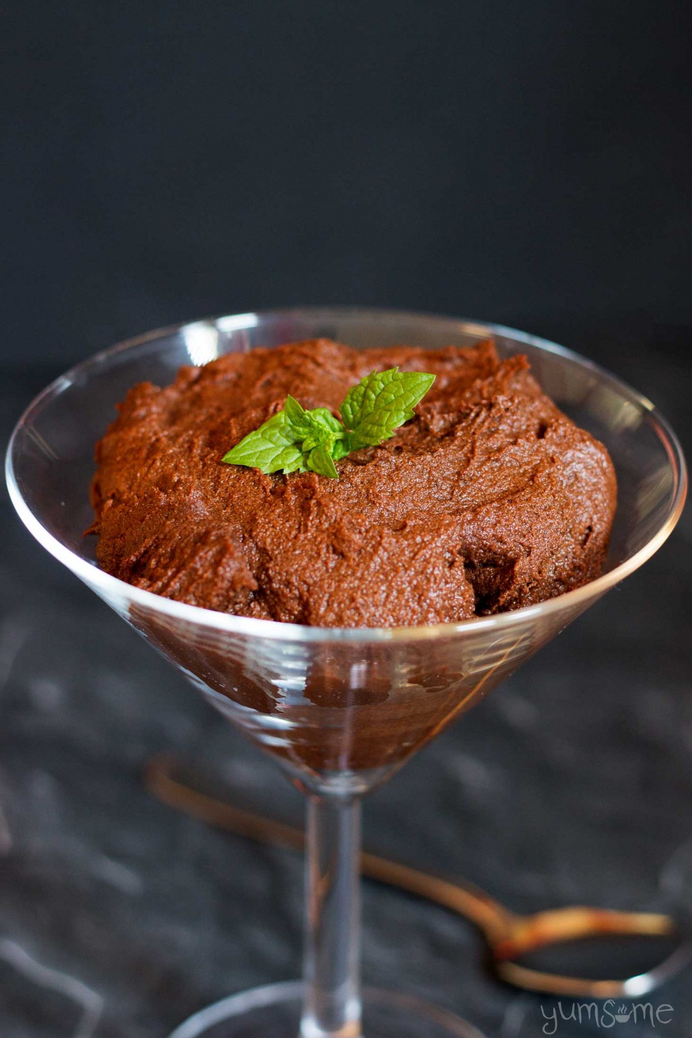 Vegan chocolate and sweet potato pudding, garnished with fresh mint, in a martini glass.