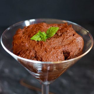 Vegan chocolate and sweet potato pudding, garnished with fresh mint, in a martini glass.