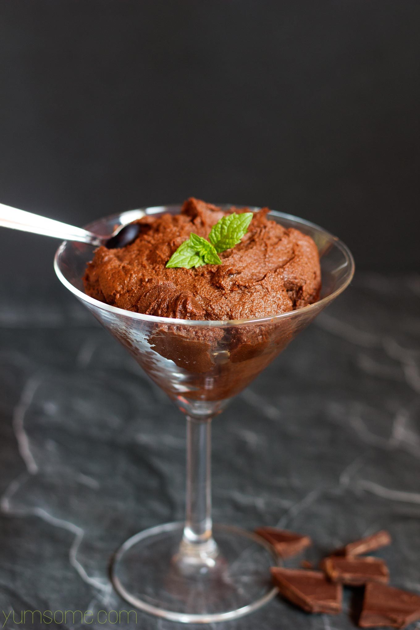A cocktail glass containing vegan chocolate maple pudding, against a dark background.