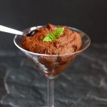 A cocktail glass containing vegan chocolate maple pudding, against a dark background.