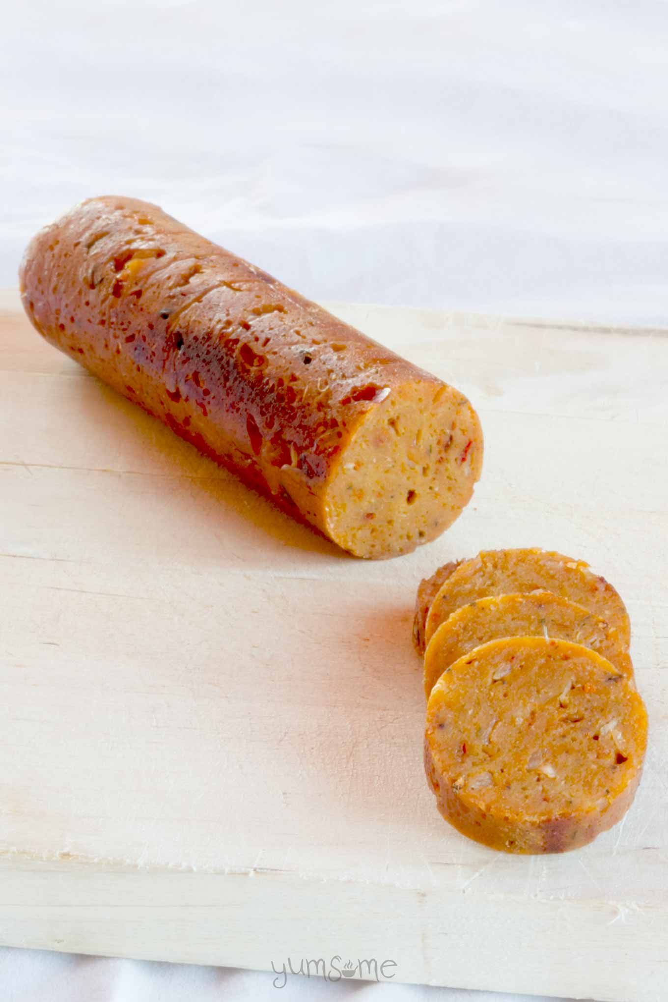 One partially cut up vegan sausage on a white background.