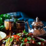 Moroccan vegetable tagine with a pot of tea and two glasses.