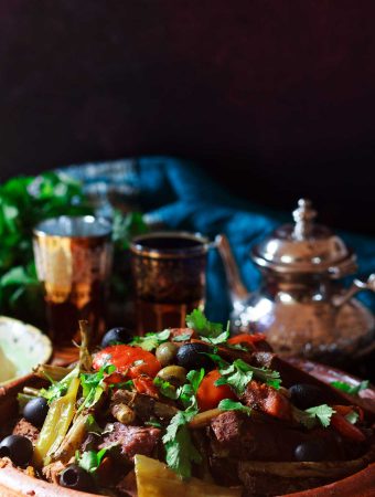 Moroccan vegetable tagine with a pot of tea and two glasses.