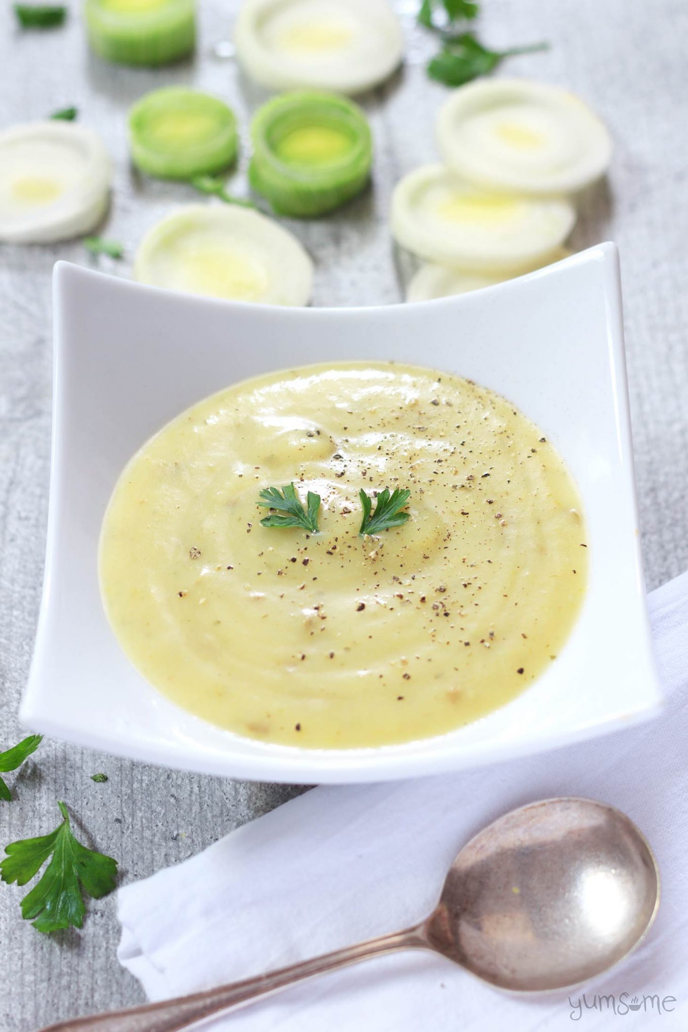 some sliced leeks and a bowl of hearty vegan potato, leek, and cheese soup | yumsome.com