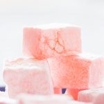 A stack of pink Turkish delight (lokum) against a pale background..