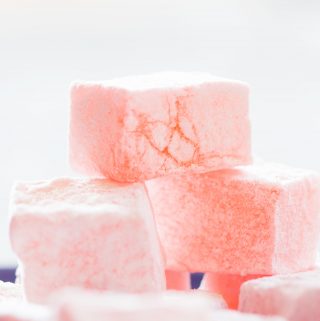 A stack of pink Turkish delight (lokum) against a pale background..