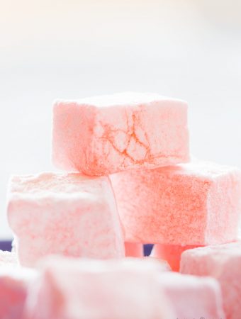 A stack of pink Turkish delight (lokum) against a pale background..