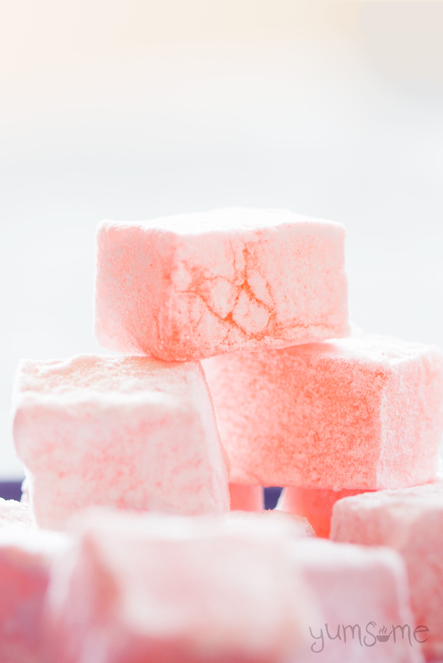 A stack of pink Turkish delight (lokum) against a pale background..