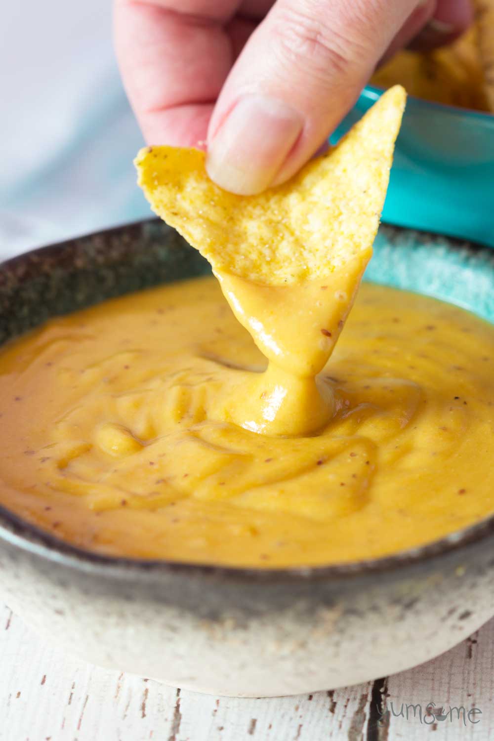 A tortilla chip dipped into a bowl of delicious vegan nacho cheese! | yumsome.com
