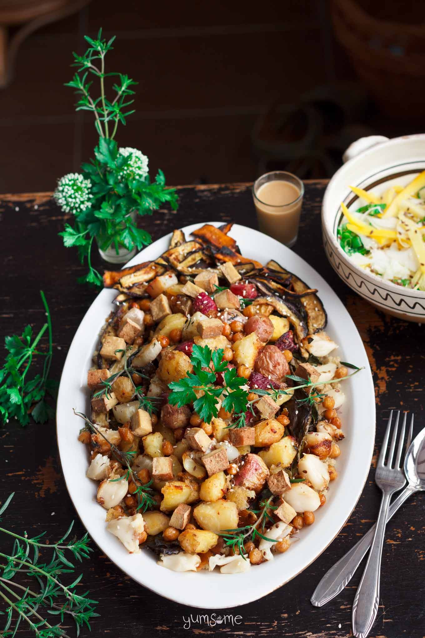 An oval plate of Roast Potato, Quinoa, and Garden Veggie Salad on a black table.