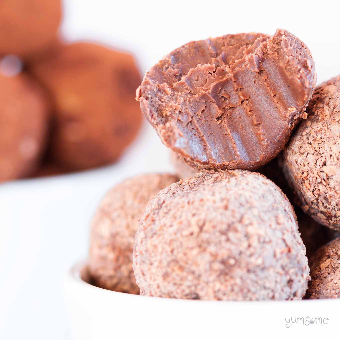 A pile of vegan raspberry chocolate truffles with a bite taken from one.