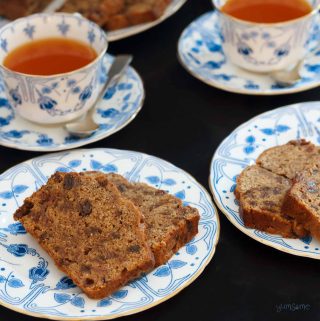 Closeup of two plates of English tea loaf and two cups of tea.