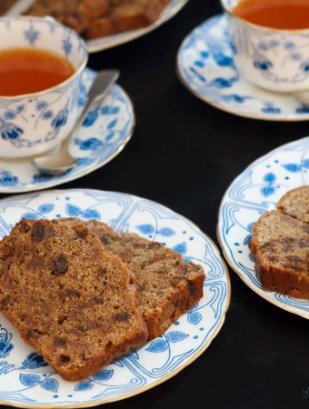 Closeup of two plates of English tea loaf and two cups of tea.