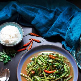 Overhead shot of a plate of vegan vegan Thai stir-fried morning glory.