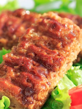 Meaty BBQ seitan ribs on a bed of green leaves.