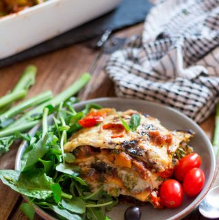 loaded vegan lasagne on a plate, plus green salad leaves and baby plum tomatoes | yumsome.com