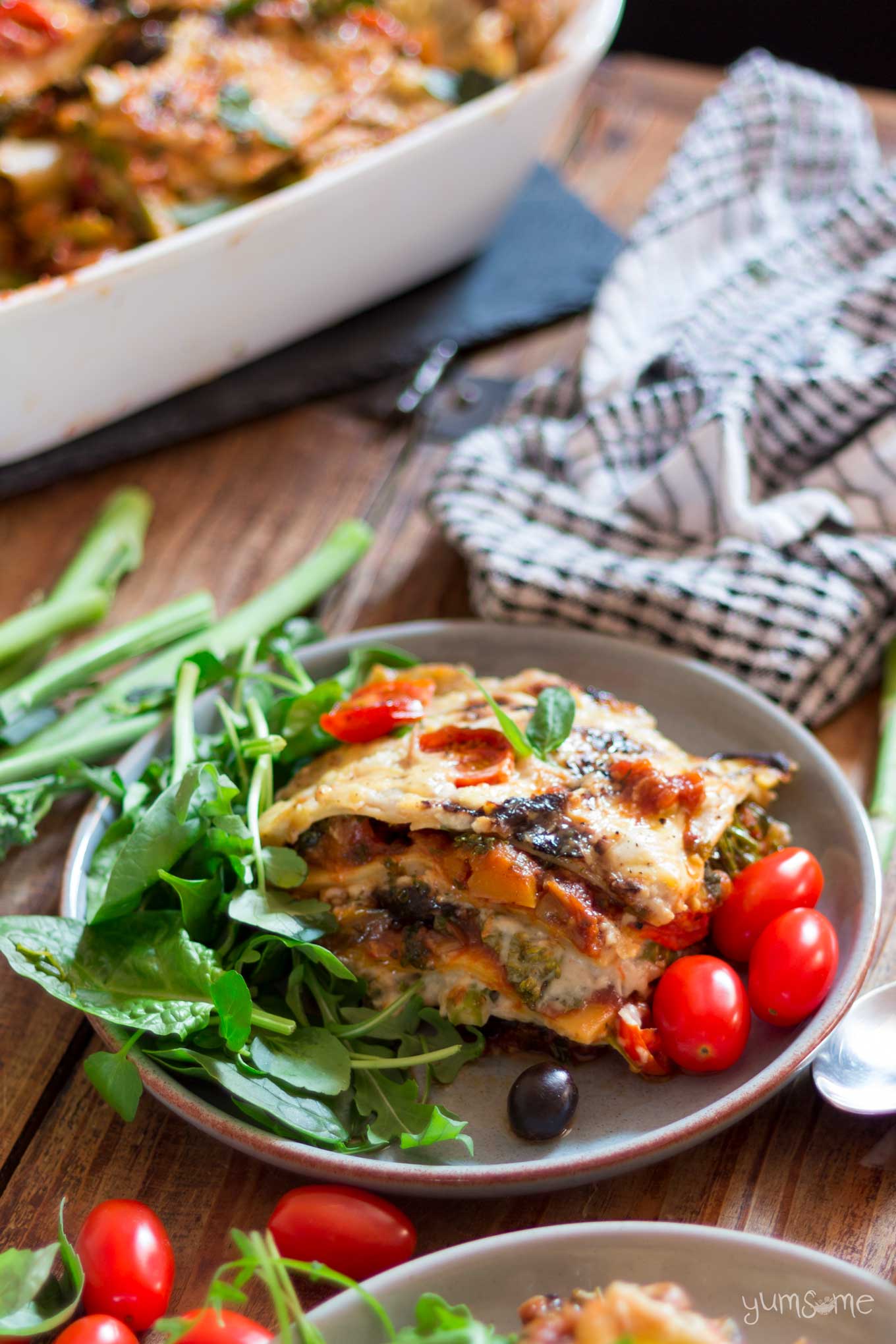 loaded vegan lasagne on a plate, plus green salad leaves and baby plum tomatoes | yumsome.com