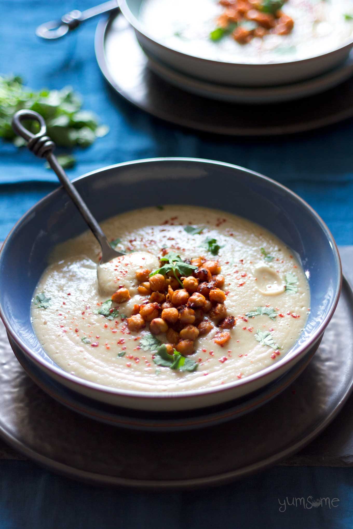A bowl of Gingery Parsnip Soup with Spicy Roasted Chickpeas on a blue background.