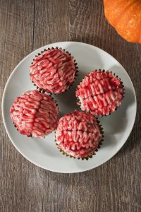 Four pink brain-like cupcakes on a white plate.