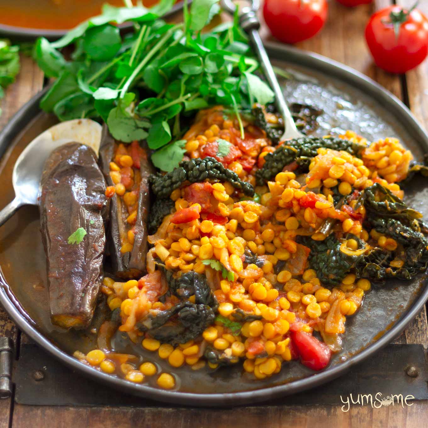 vegan spicy dal, aubergine, and kale casserole on a plate, and salad | yumsome.com