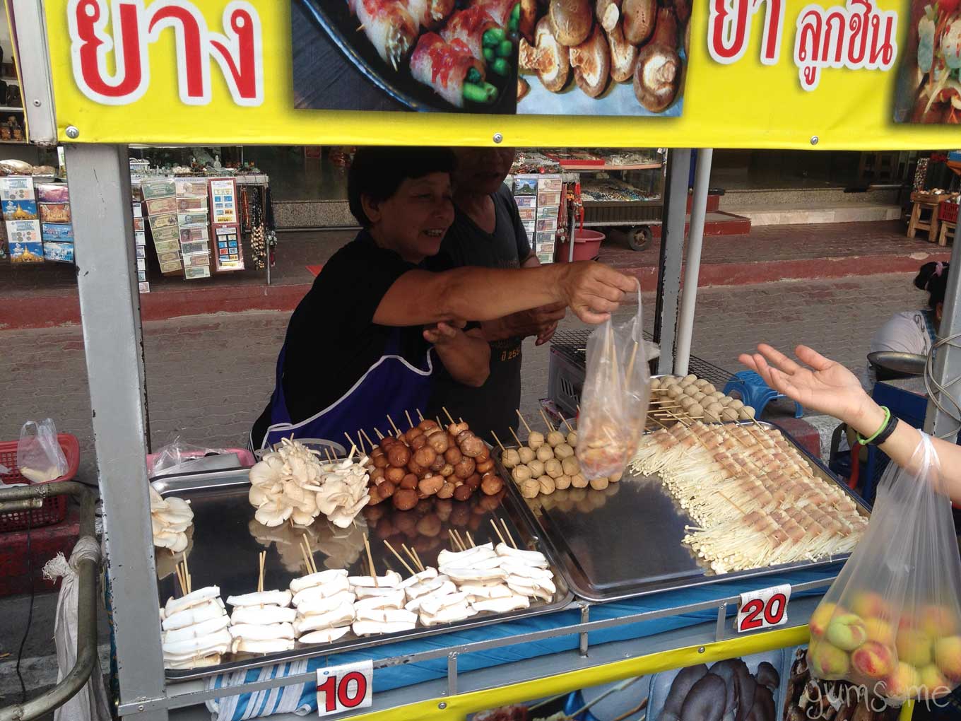 A Thai woman hands over a bag of food at a street food cart in Mae Sai, Thailand.