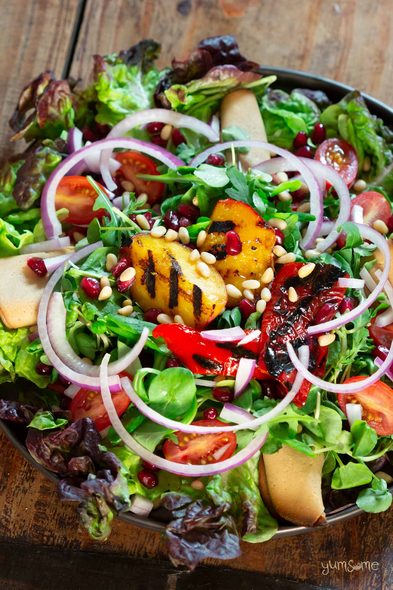A colourful plate of grilled nectarine salad on a wooden table.
