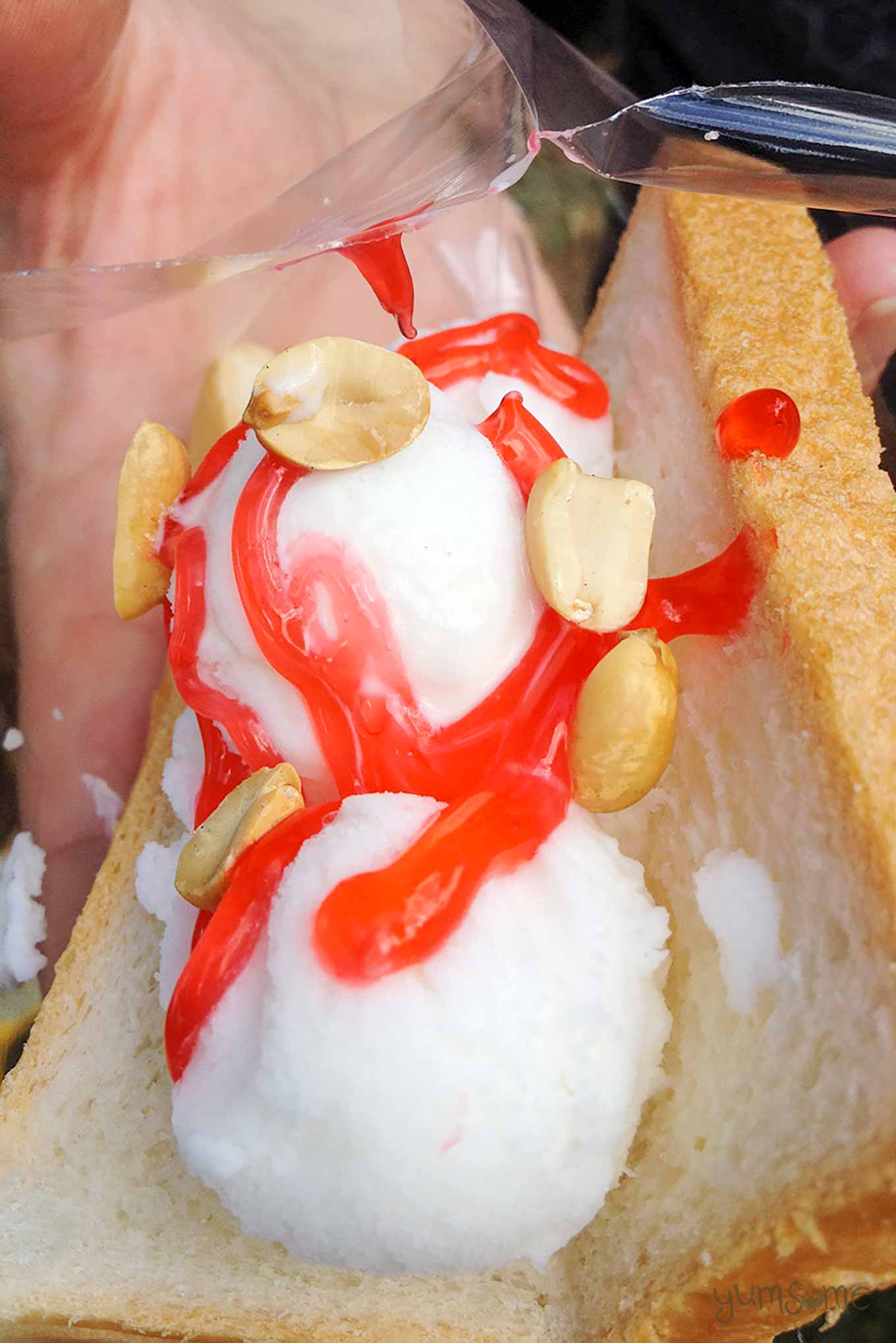 A Thai coconut ice cream sandwich with strawberry syrup and peanuts.