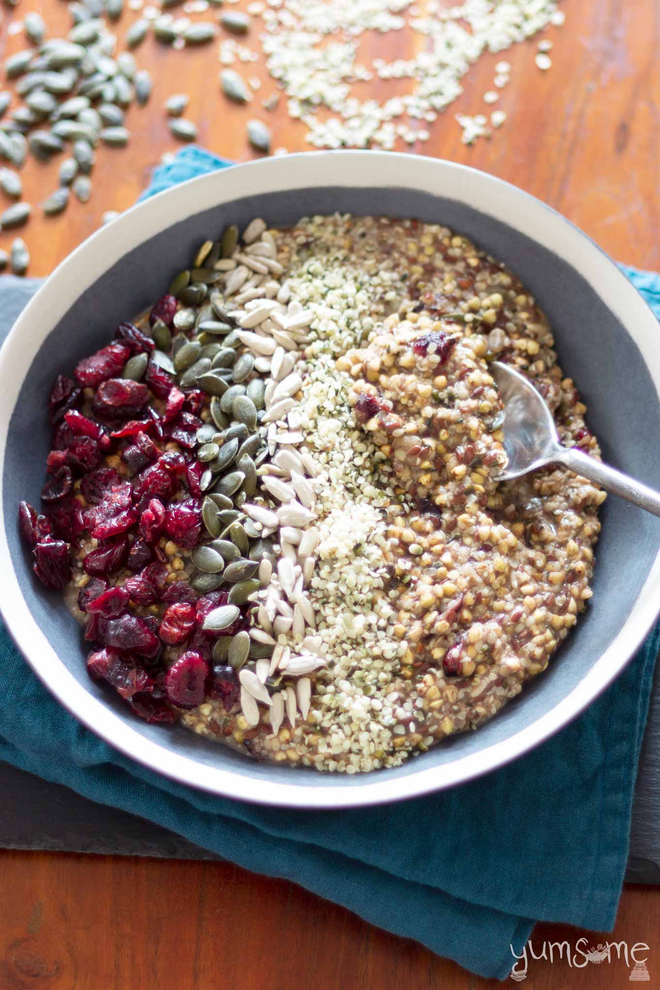 A bowl of hemp and buckwheat porridge with a selection of seeds and dried fruit toppings.