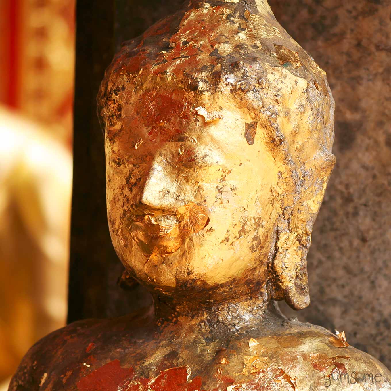 An old golden Buddha statue, with flaking gold leaf, showing signs of repeated repair.