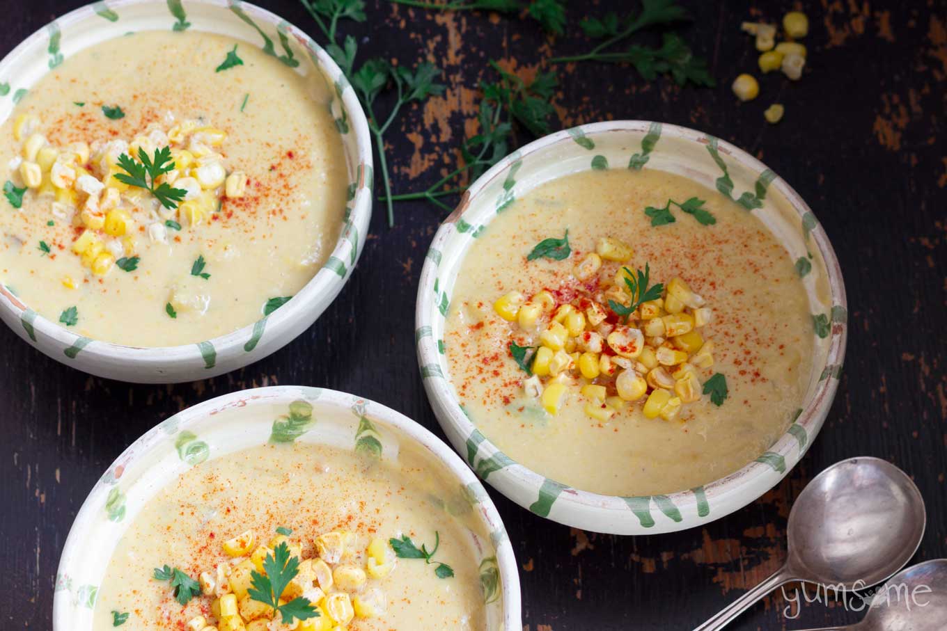 A black table with three bowls of sweetcorn chowder.