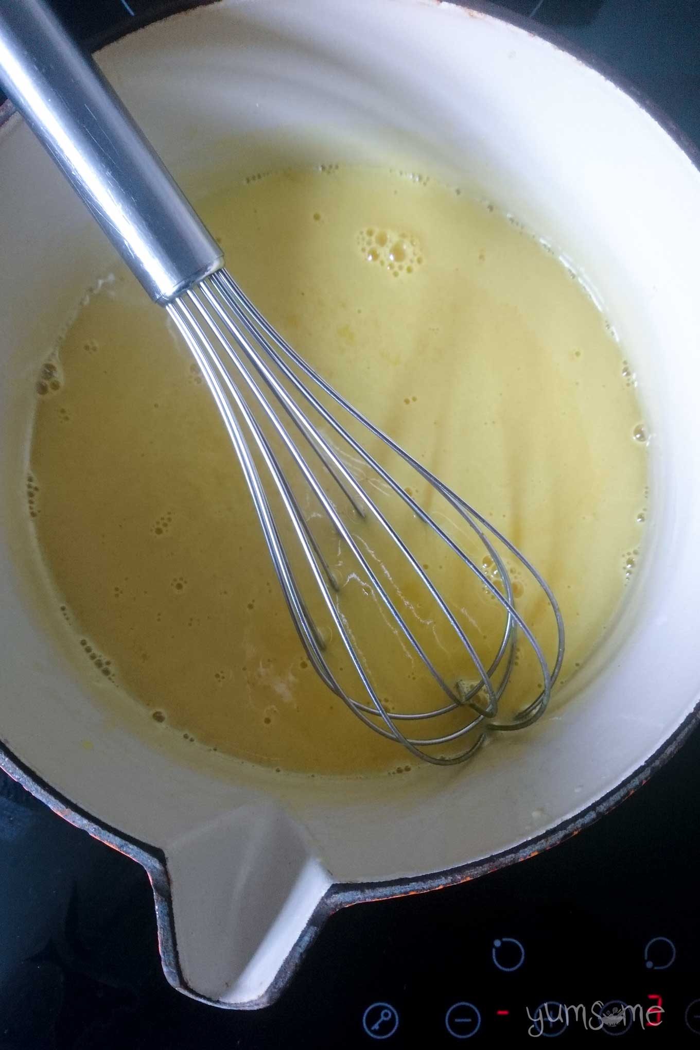 Thin lemon curd slurry in a pan, with a whisk, before cooking.