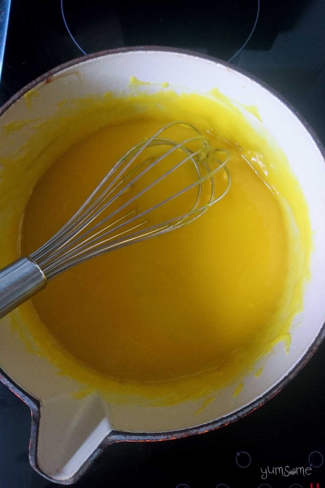 Thickened and cooked lemon curd in a pan, with a whisk.