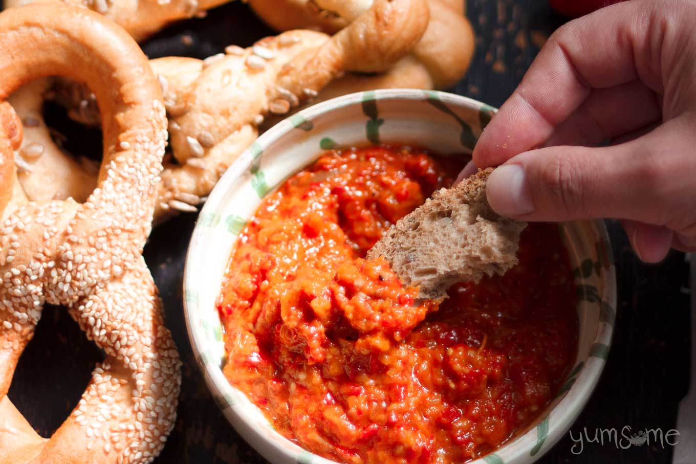 A small piece of bread dipped into a bowl of zacusca.