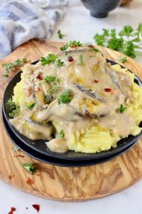 A bowl of mashed potatoes covered in vegan shiitake mushroom gravy.
