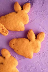 Several biscuits in the shape of bunnies on a purple background.