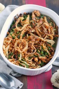 A large white dish of green bean casserole, topped with fried onions.
