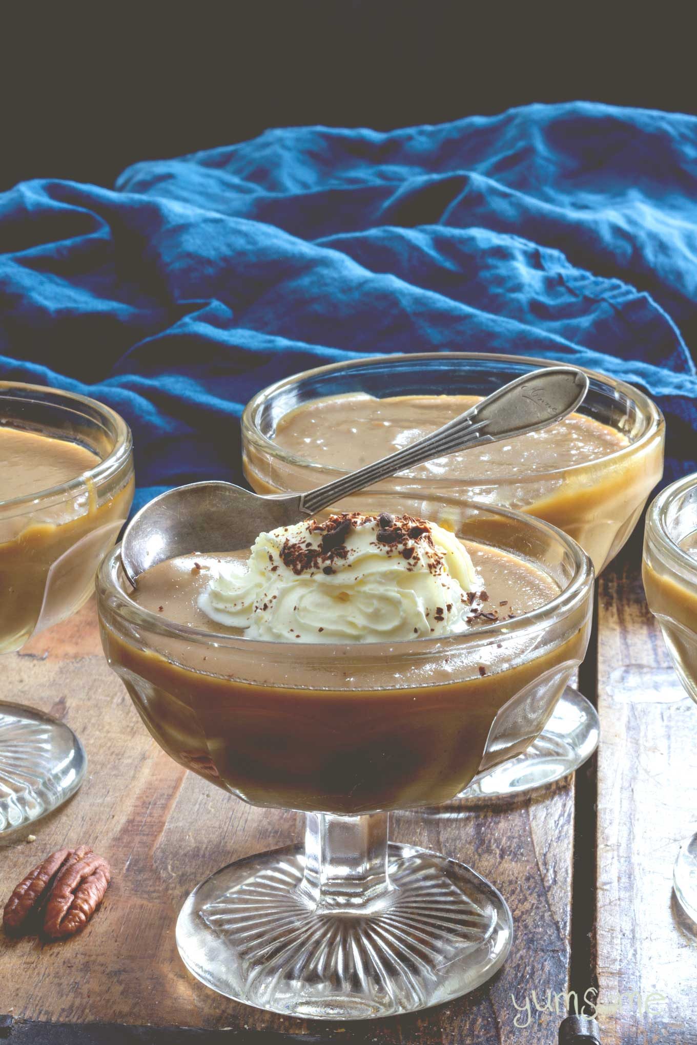 Vegan butterscotch pudding in glass bowls, against a purple and blue background.