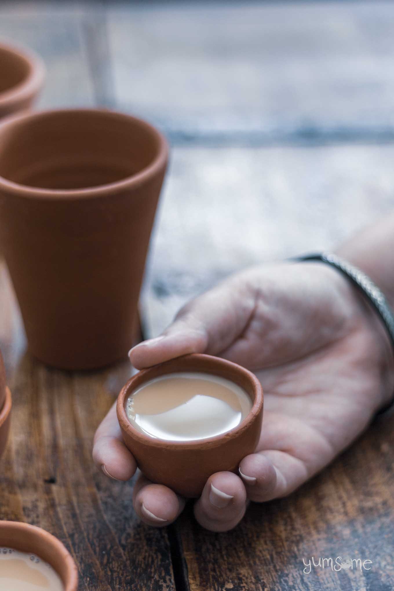 A hand holding a small cup of masala chai.