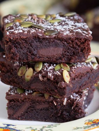 Closeup shot of three fudge brownies in a stack on a yellow plate.