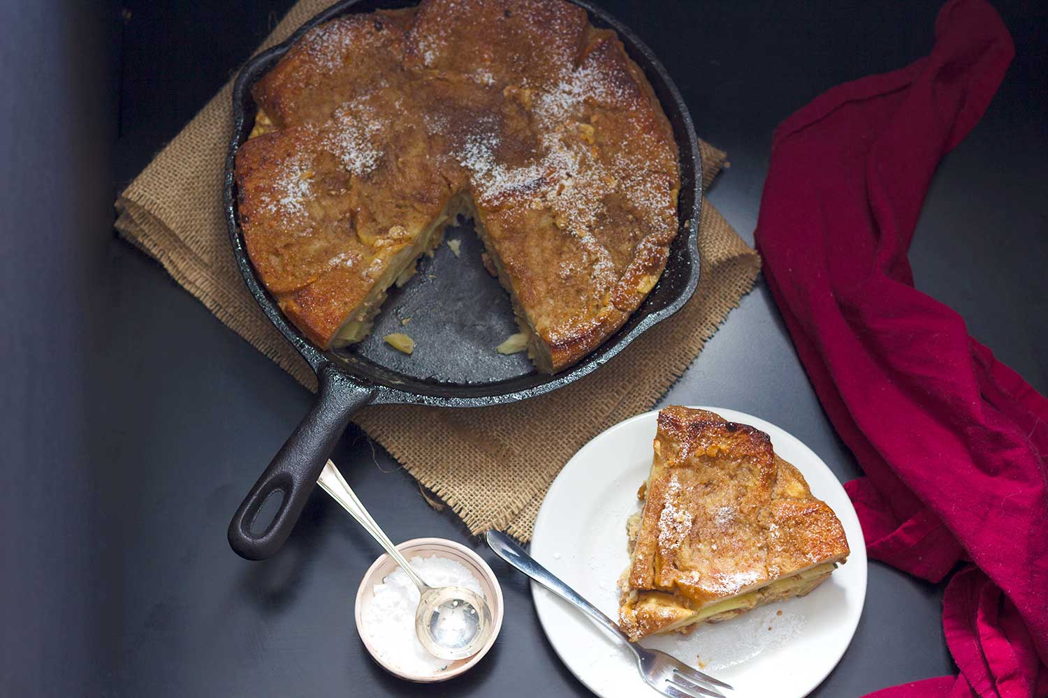 Overhead view of a cast iron skillet and a white plate with zemlbába.